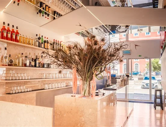 Balcão de mármore e área de bar do restaurante Casanova com prateleiras de bebidas, copos de vidro e arranjo decorativo.