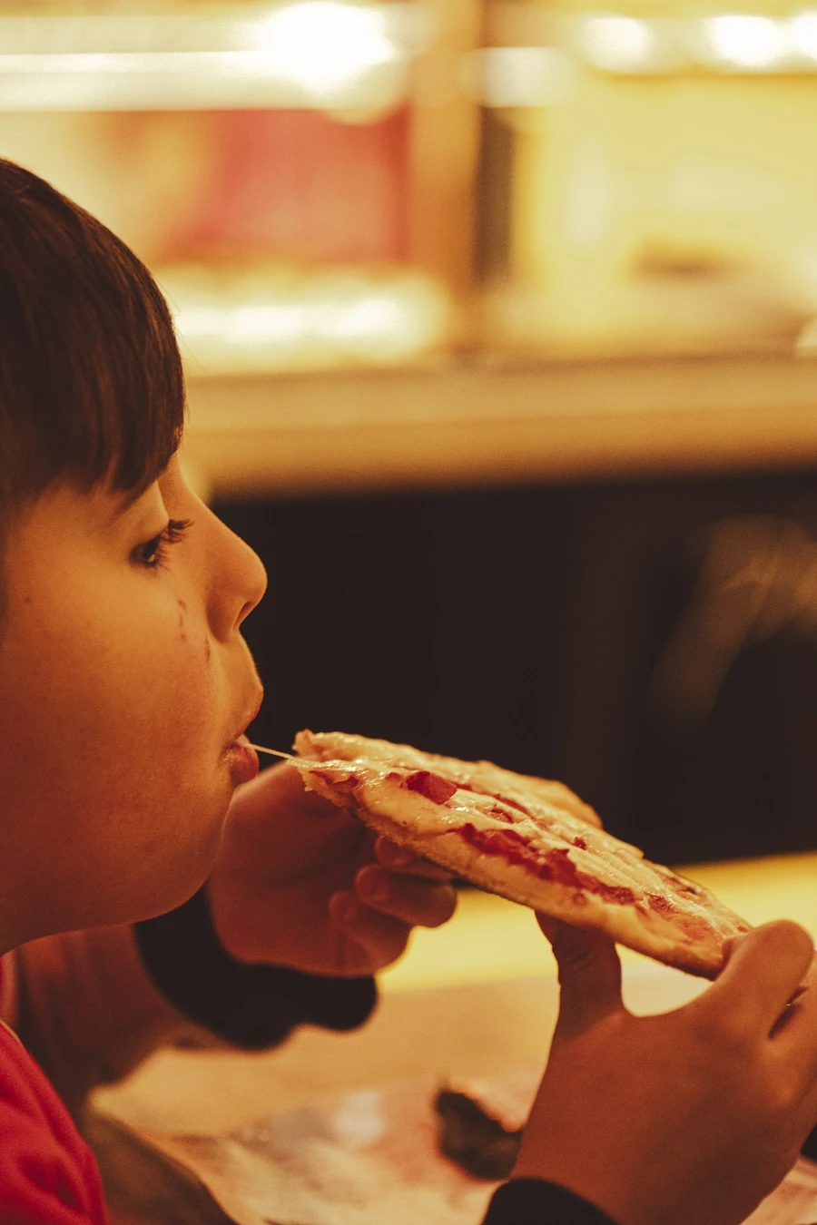 menino comendo fatia de pizza em pizza a pezzi