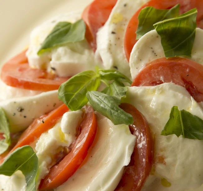 Salada caprese tradicional italiana com fatias de tomate, queijo mozzarella fresco e folhas de manjericão no Casa Nostra.